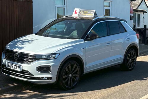 White Volkswagen SUV parked on a residential street with an L-plate on the roof, indicating a driving school car.